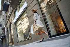 完整的长度年轻的时尚的女人购物袋进入时尚店里商店城市微笑