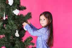 孩子们假期圣诞节概念女孩装修圣诞节树粉红色的背景