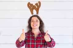 快乐美丽的女人圣诞节服装鹿角头手势拇指白色背景