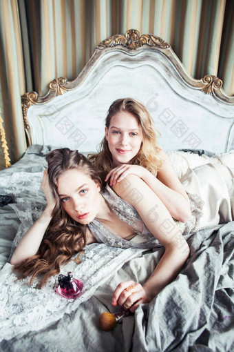 漂亮的双胞胎妹妹金发碧眼的卷曲的发型女孩奢侈品房子室内丰富的年轻的人概念