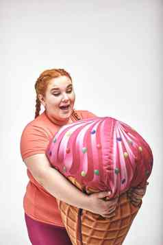 红色的头发的胖乎乎的女人持有巨大的冰奶油