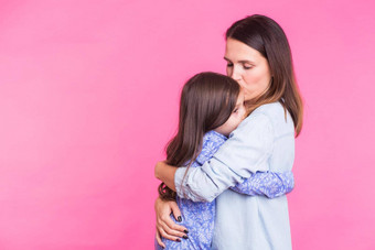 人幸福爱家庭母亲概念快乐女儿拥抱接吻妈妈。粉红色的背景