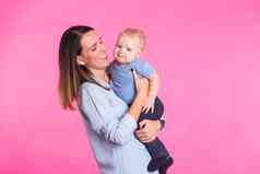 家庭母亲育儿人孩子护理概念快乐妈妈。持有可爱的婴儿粉红色的背景