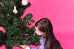 孩子们假期圣诞节概念女孩装修圣诞节树粉红色的背景