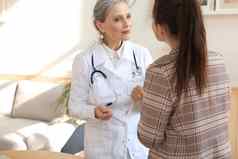 友好的中间岁的女医生鼓励支持病人医疗检查