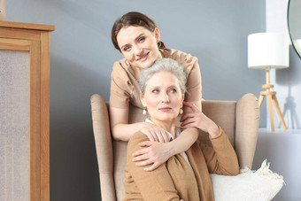 快乐女儿拥抱老妈妈。站椅子生活房间享受温柔的时刻首页