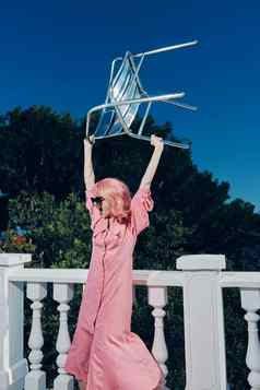 时尚女人粉红色的衣服现代风格站栏杆生活方式