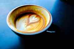 杯热拿铁咖啡爱心形状泡沫牛奶黑暗背景