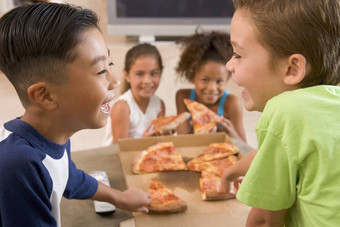 年轻的孩子们在室内吃披萨微笑