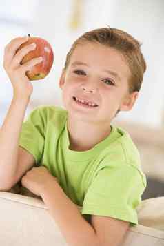年轻的男孩吃苹果生活房间微笑