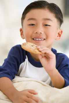 年轻的男孩吃饼干生活房间微笑