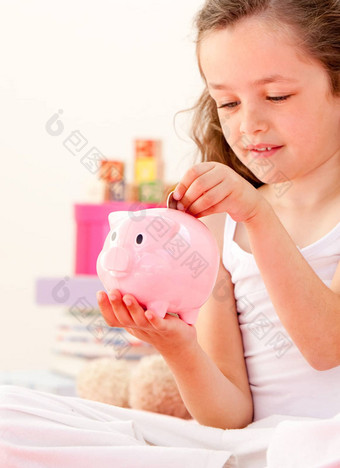 可爱的女孩储蓄钱储蓄罐坐着床上