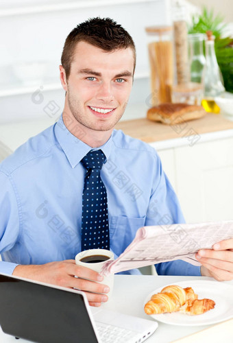 英俊的商人阅读报纸喝咖啡