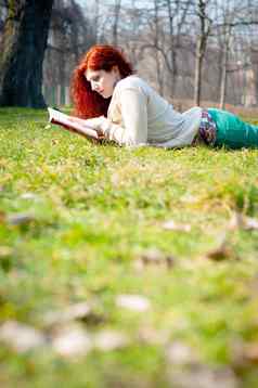 美丽的红色的头年轻的女人阅读书
