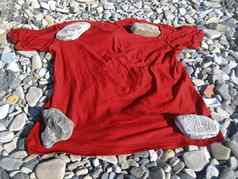 红色的t恤躺海岸石头