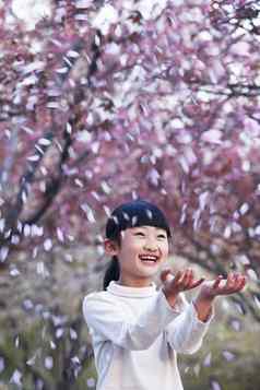 快乐年轻的女孩扔樱桃开花花瓣空气公园春天