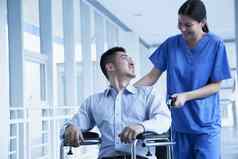 微笑女护士推协助病人轮椅医院