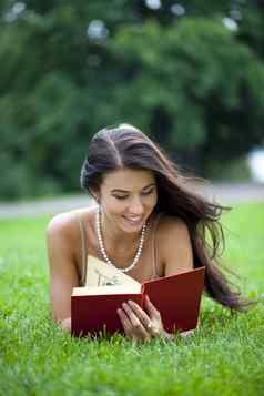 年轻的美丽的年轻的女人阅读书户外