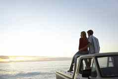 后视图年轻的夫妇拾音器卡车停前面海洋享受日落