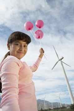 低角视图年轻的女孩玩粉红色的气球风农场