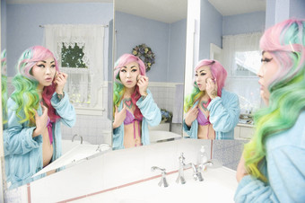 年轻的女人应用化妆多个镜子反射
