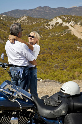 高级夫妇拥抱摩托车沙漠