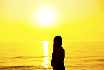年轻的女人站海滩日落光