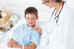 医生令人欣慰的生病的男孩病房