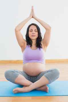 怀孕了浅黑肤色的女人坐着席莲花构成冥想