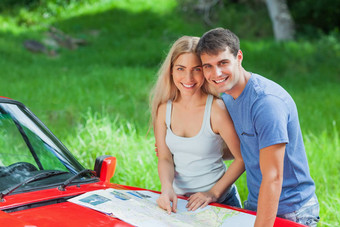 快乐年轻的夫妇阅读地图蓬式汽车阀盖