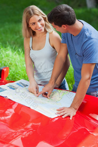 微笑年轻的夫妇阅读地图蓬式汽车阀盖