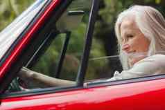 快乐的成熟的女人开车红色的可转换