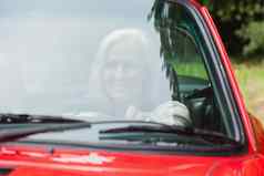 快乐的成熟的女人开车红色的蓬式汽车