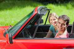 快乐的年轻的夫妇骑红色的蓬式汽车