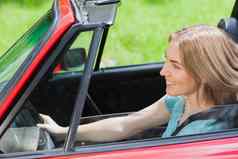 微笑女人开车红色的蓬式汽车