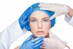 外科医生检查平静金发女郎穿蓝色的外科手术帽