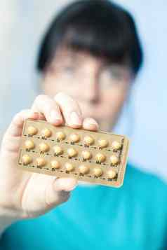 年轻的女人持有出生控制药片