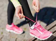 跑步者女人用带子束紧培训师鞋子