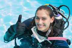 微笑女人潜水培训游泳池显示拇指