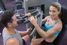 个人教练训练微笑女健美运动员重量机