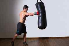 赤膊上阵肌肉发达的拳击手冲袋健身房