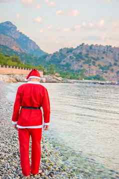 男人。穿着圣诞老人老人走海岸