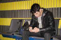 年轻的男人。打字智能手机等待地铁火车
