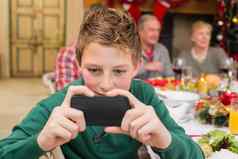 年轻的男孩持有智能手机圣诞节晚餐
