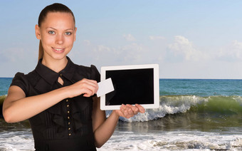 美丽的女商人持有平板电脑业务卡前面屏幕海景呵呵潮汐波背景