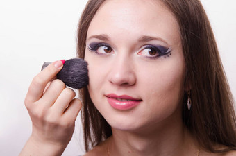 化妆艺术家适用于粉脸美丽的模型
