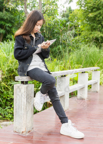 年轻的女孩平板电脑电脑公园