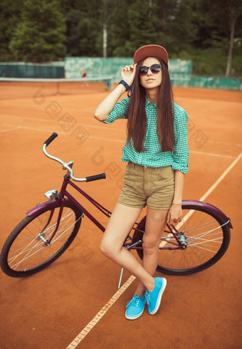 女孩赶时髦的人站<strong>品红</strong>色的自行车网球法院