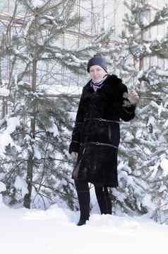 快乐的女人黑色的皮毛外套成本白雪覆盖的销