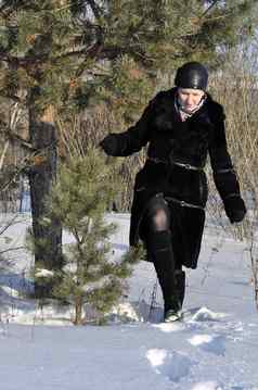 女人黑色的皮毛外套使雪雪地里